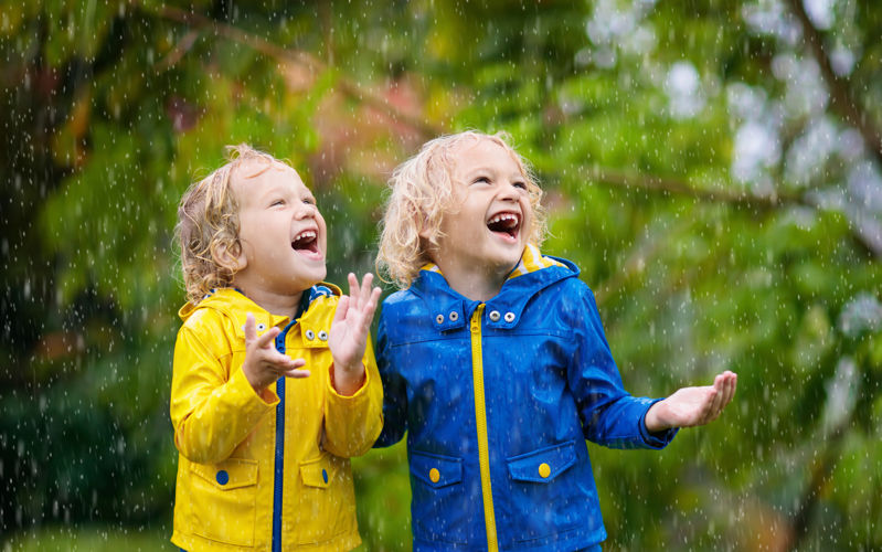 Two boys in raincoats laughing in the rain