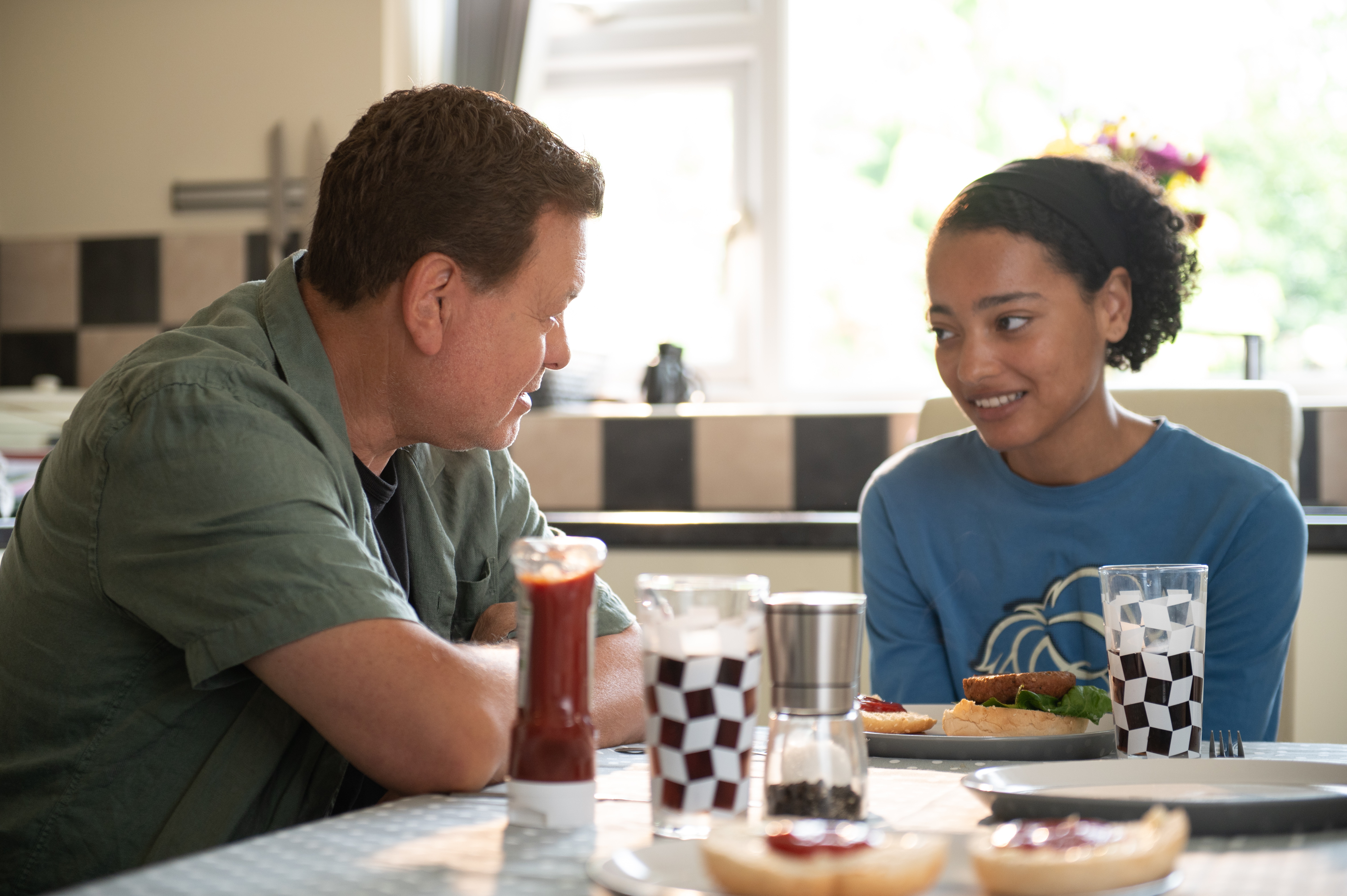 Young girl sat at the kitchen table with foster dad