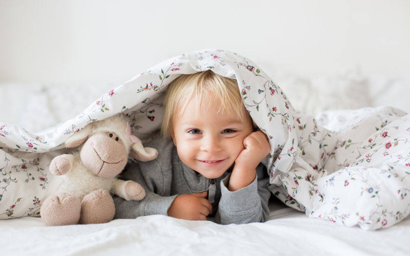 Girl smiling at camera with quilt over her head