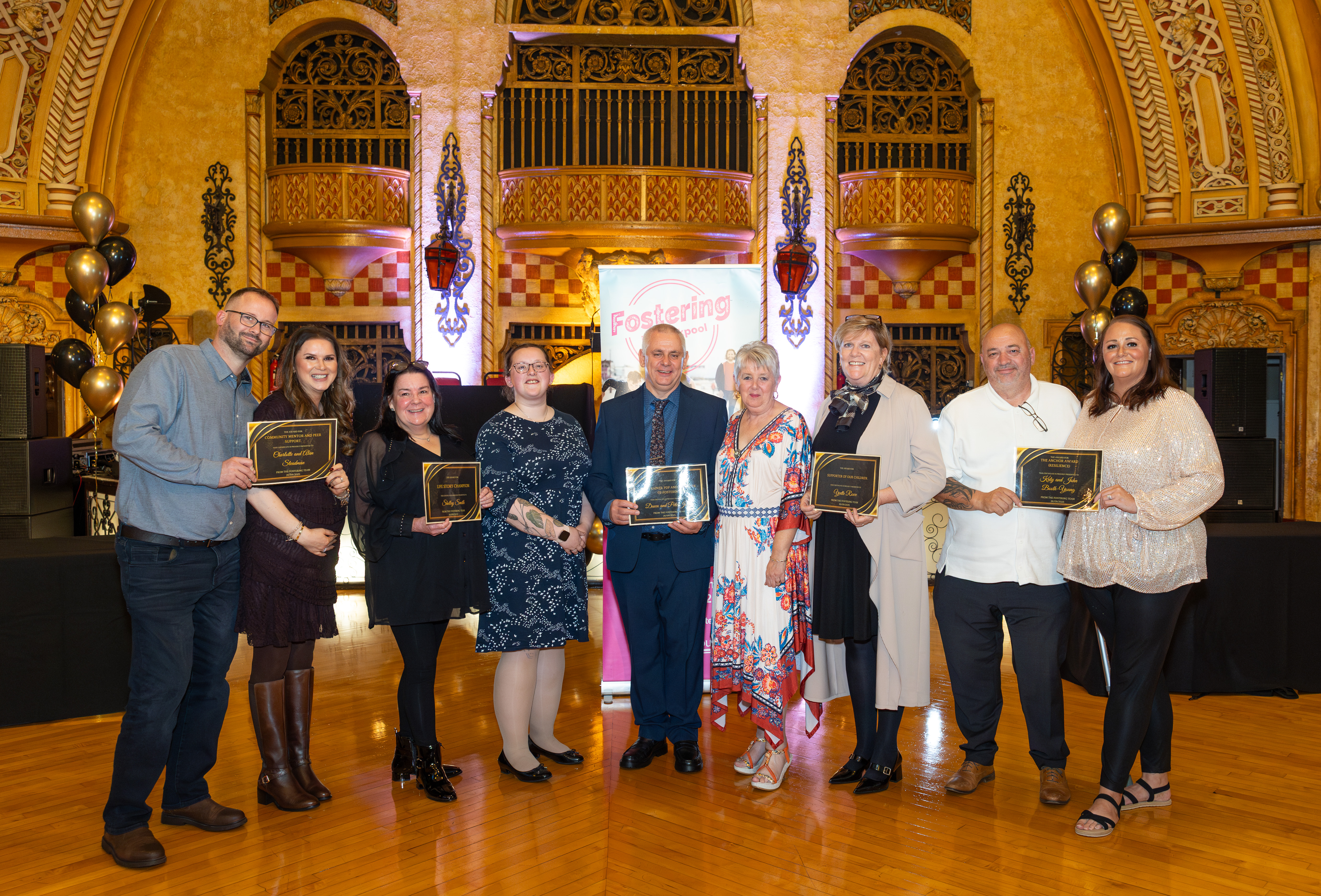 Foster carer award winners stood in a line smiling