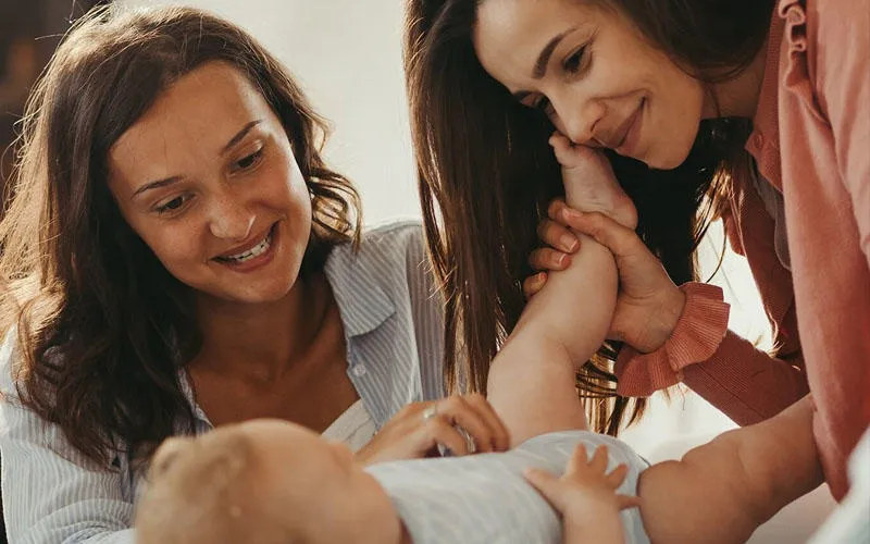 Two carers playing with a baby.